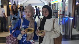 Dua pelanggan PT KAI Daop 2 memperlihatkan makanan gratis yang dibagikan Daop 2 Bandung di momen Hari Pangan Seduania. PJ/Dok