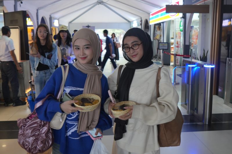 Dua pelanggan PT KAI Daop 2 memperlihatkan makanan gratis yang dibagikan Daop 2 Bandung di momen Hari Pangan Seduania. PJ/Dok
